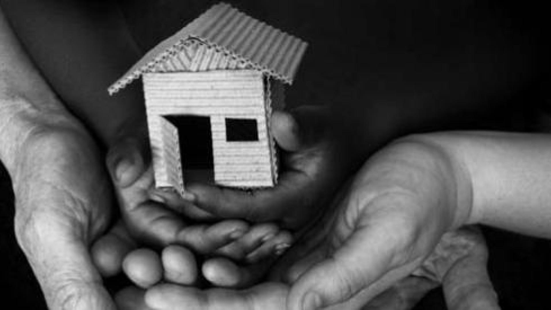 Three sets of hands holding a small symbolic house
