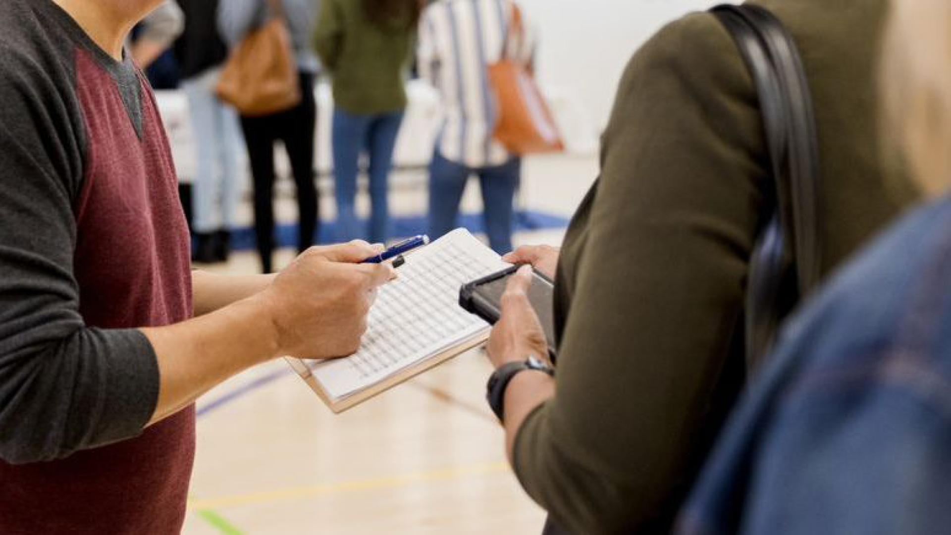 A person registers a voter in a school gymnasium