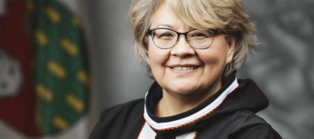 Minister Lucy Kuptana in front of the NWT Flag